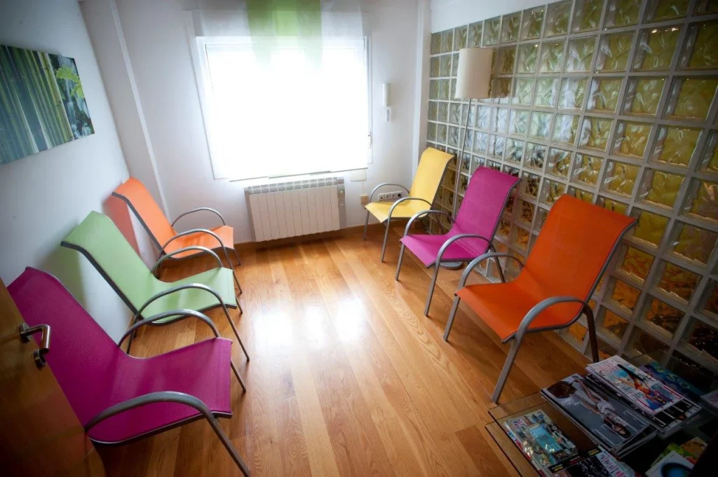 Sala de espera con asientos de colores y pared de bloques de vidrio